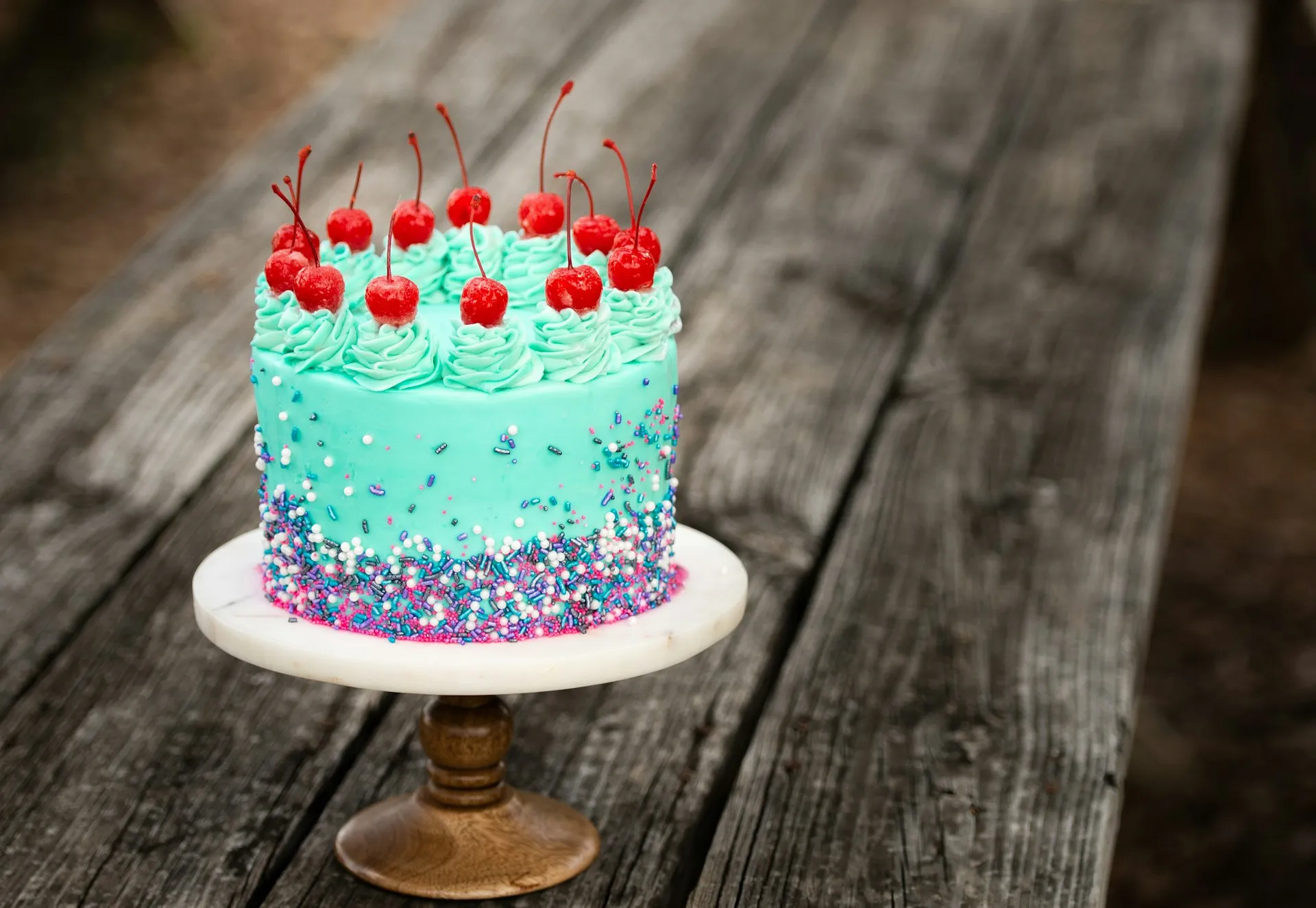 Tarta turquesa de cumpleaños con cerezas y decoración de colores
